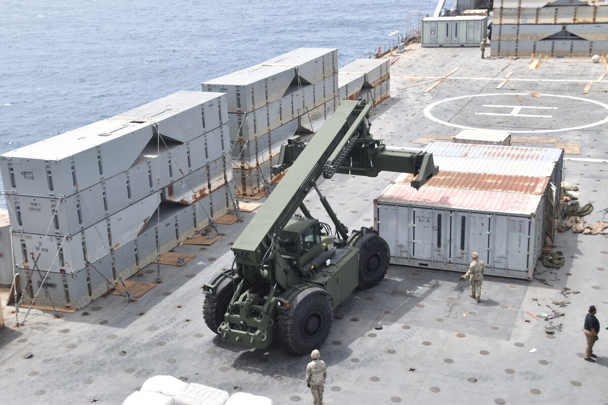 Service members assemble a temporary pier using military equipment.