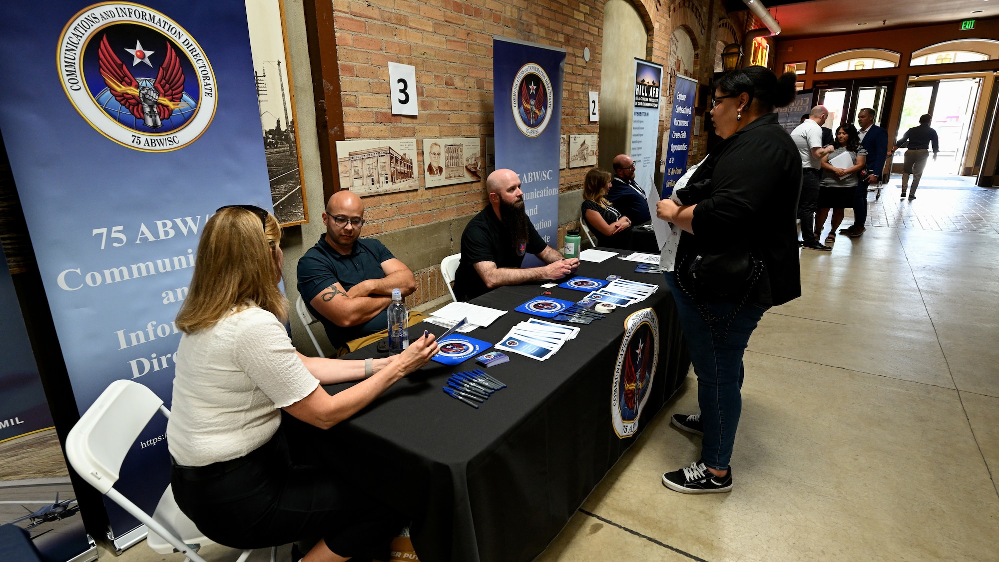 A woman speaks to HR specialists sitting behind an information booth about jobs at Hill AFB.