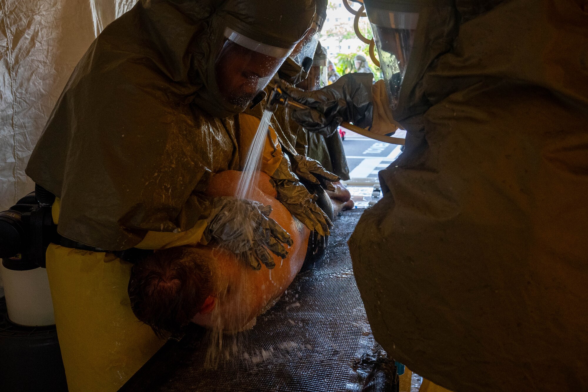 Airmen gets their back cleaned during a DECON shower