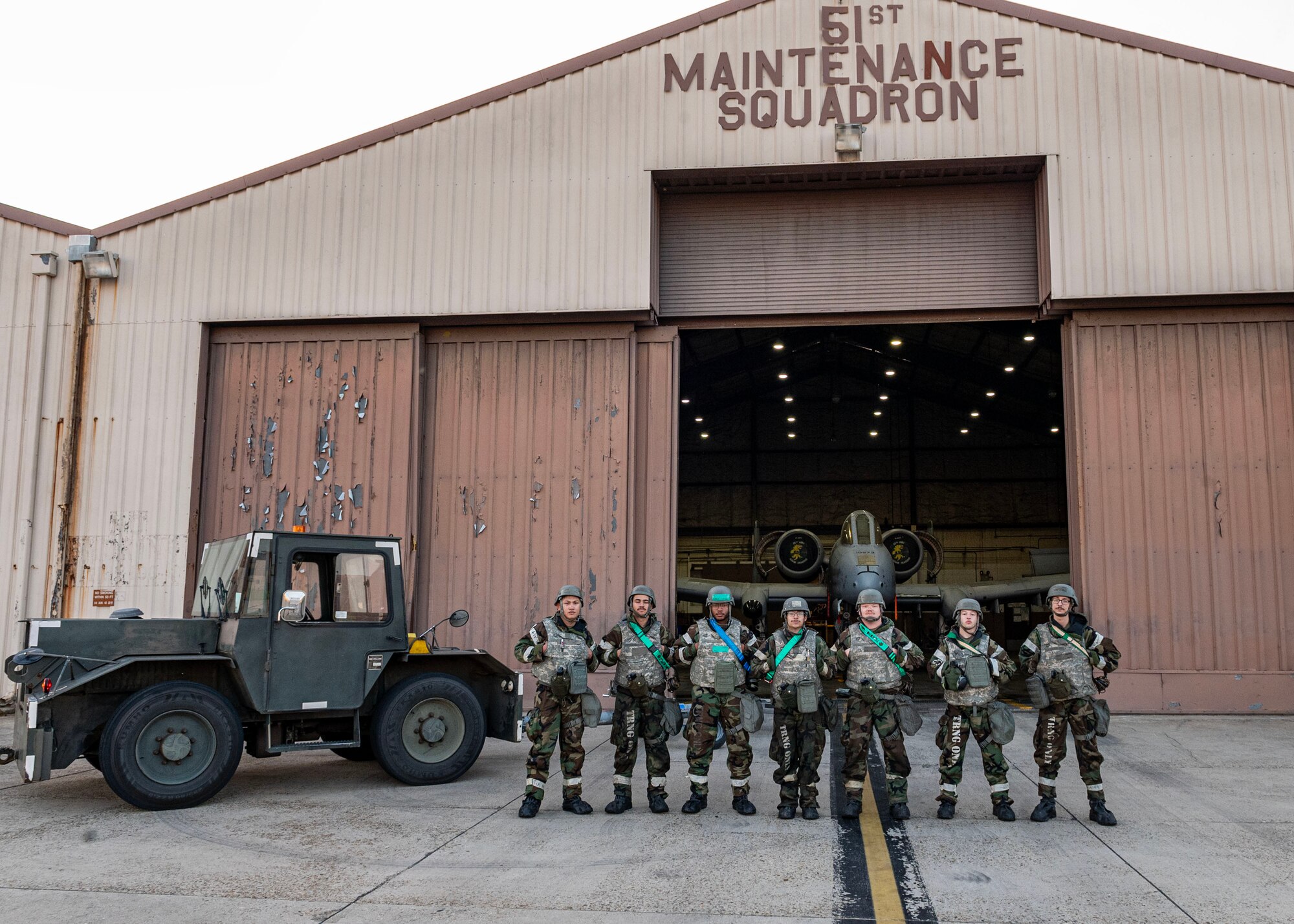U.S. Air Force crew chiefs assigned to the 25th Fighter Generation Squadron stand in front of a maintenance hangar while in mission-oriented protective posture level two during Beverly Herd 24-1 at Osan Air Base, Republic of Korea, May 16, 2024. The A-10 Thunderbolt II assigned to the 25th Fighter Squadron offers maneuverability at low airspeeds and altitude while maintaining a highly accurate weapons-delivery platform, supporting the Airmen of the 51st Fighter Wing to execute the mission. Training is conducted throughout the year to generate combat airpower at a moment’s notice, affirming the commitment to the Republic of Korea remains ironclad and ensures regional stability throughout the U.S. Indo-Pacific Command. (U.S. Air Force photo by Staff Sgt. Aubree Owens)