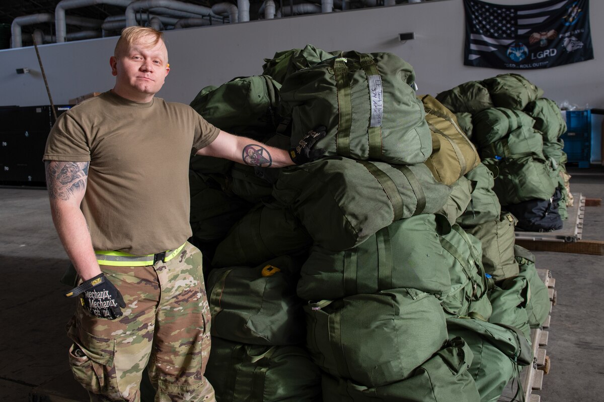 An airman next to a pallet of cargo, duffel bags.