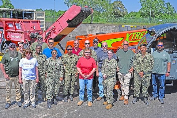 A group photo in front of a shredder and material handling equipment.