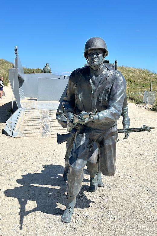 Statue of a kneeling service member on a beach.