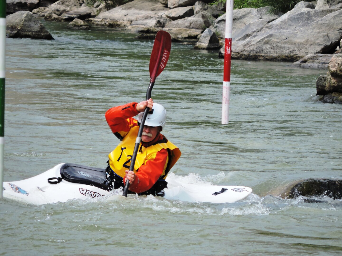 A man manuevers his kayak in a river with a paddle.