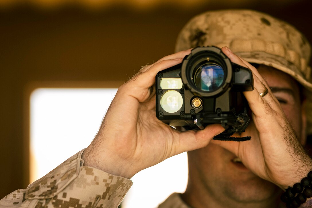 A close-up of a Marine looking through a device.