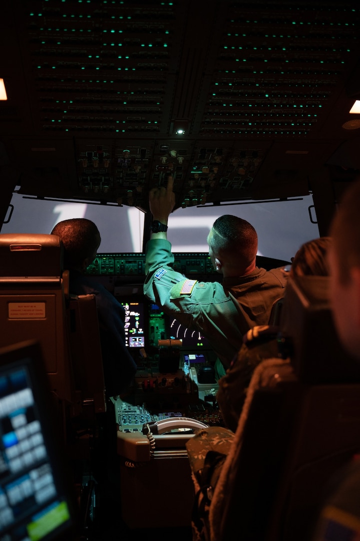 Maj. Bryant Burns, a pilot with the 157th Operations Group, prepares the KC-46 simulator with Col. Domingos Correia, director of national defense and a pilot for the Cabo Verde Armed Forces, during a base tour May 7, 2024, at Pease Air National Guard Base in Newington, N.H.