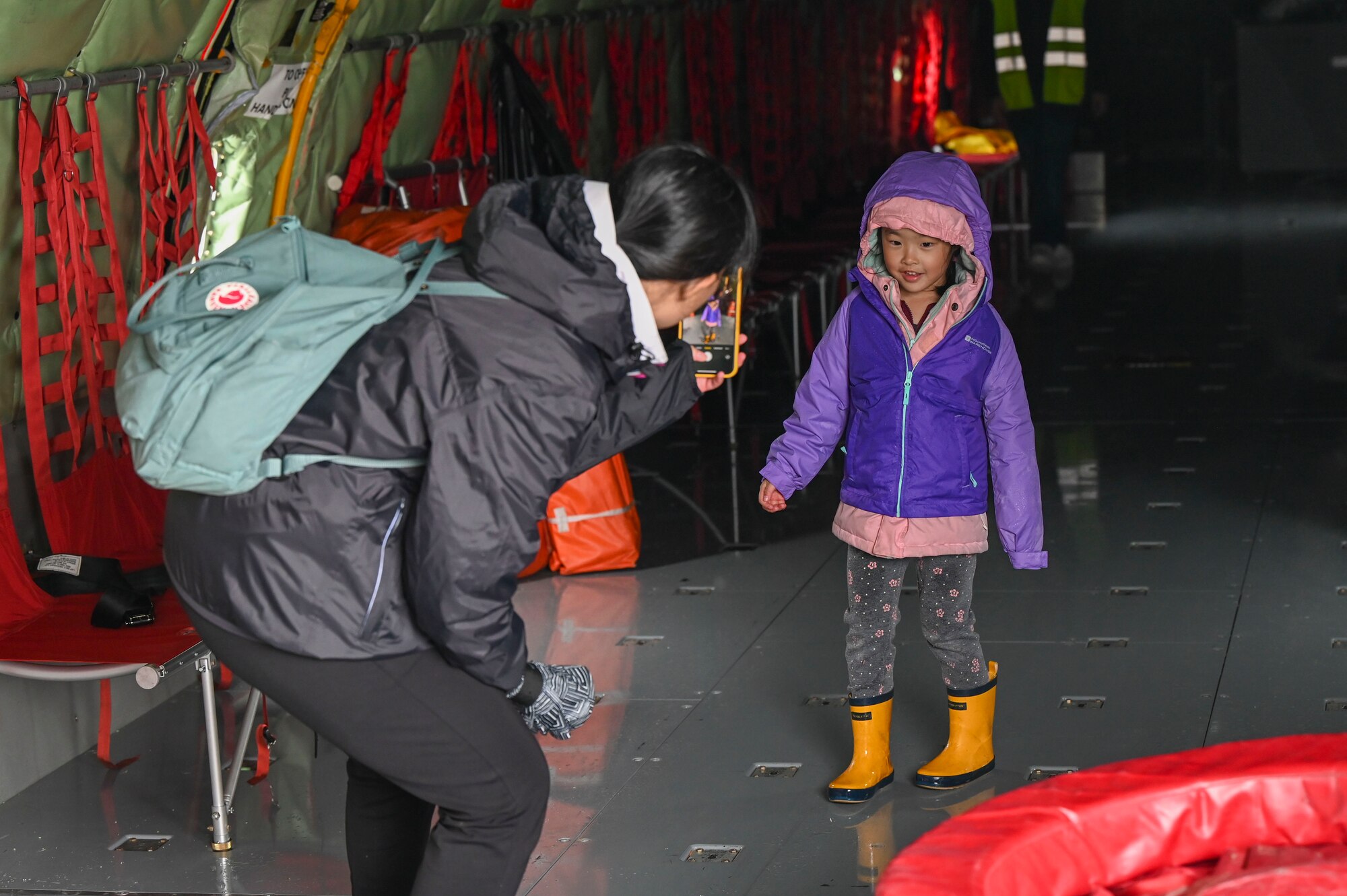 A woman takes a photo of her child inside of a jet.