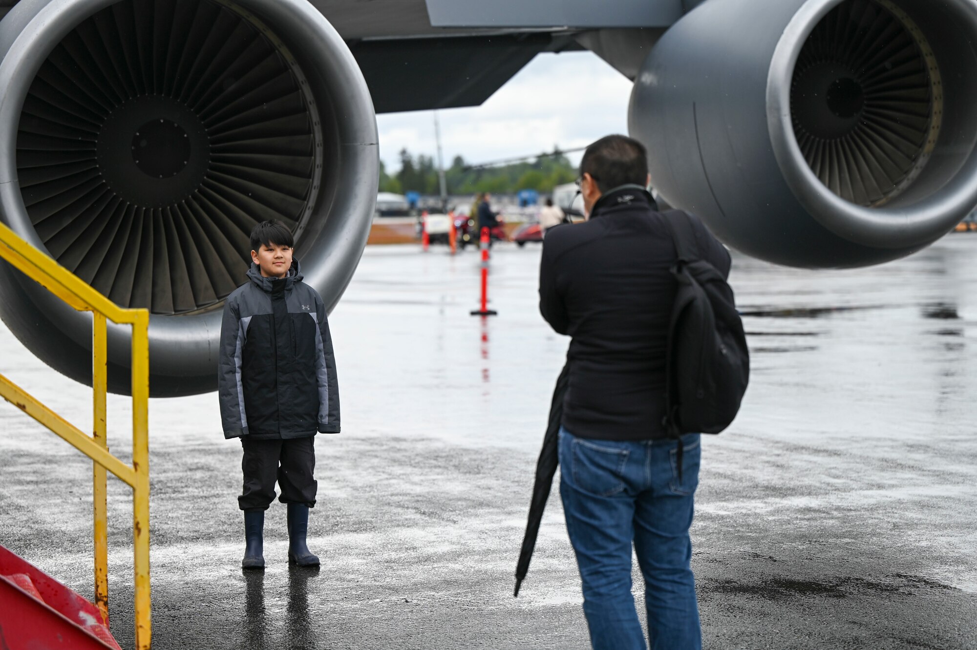 A man takes a photo of a child in front of a KC-135 Stratotanker.