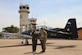 A photo of two military members in front of an aircraft.