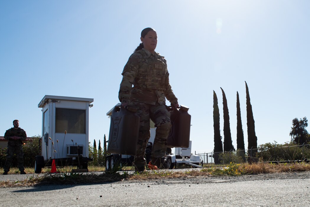Airman runs with water jugs during a Warrior Challenge