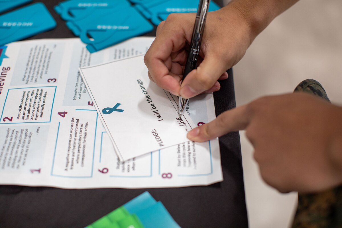 A service member writes on a small pledge card.