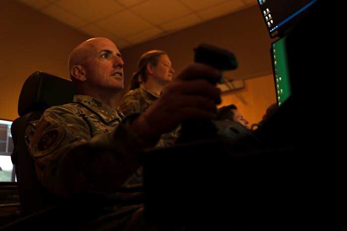 A man in a military uniform controls a joystick.