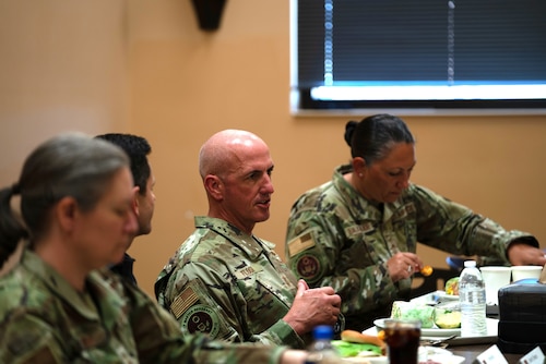 A man in a military uniform speaks to members seated at a table.