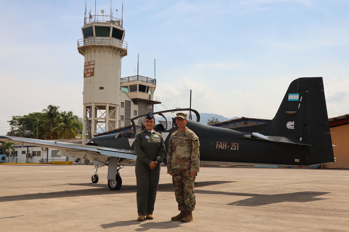 A photo of two military members in front of an aircraft.