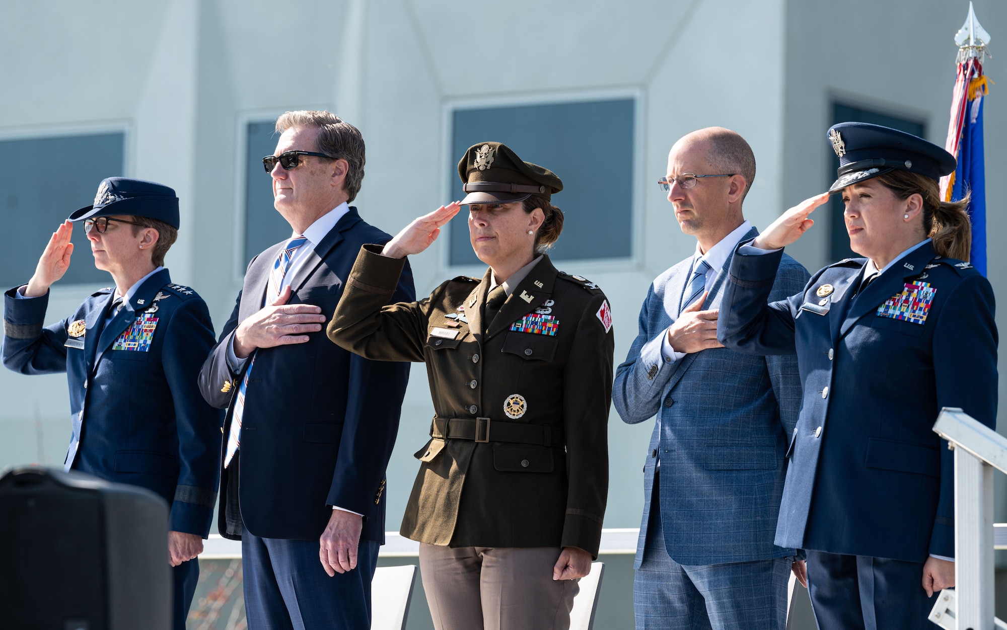 5 people standing and rendering customs and courtesies to the flag during the national anthem