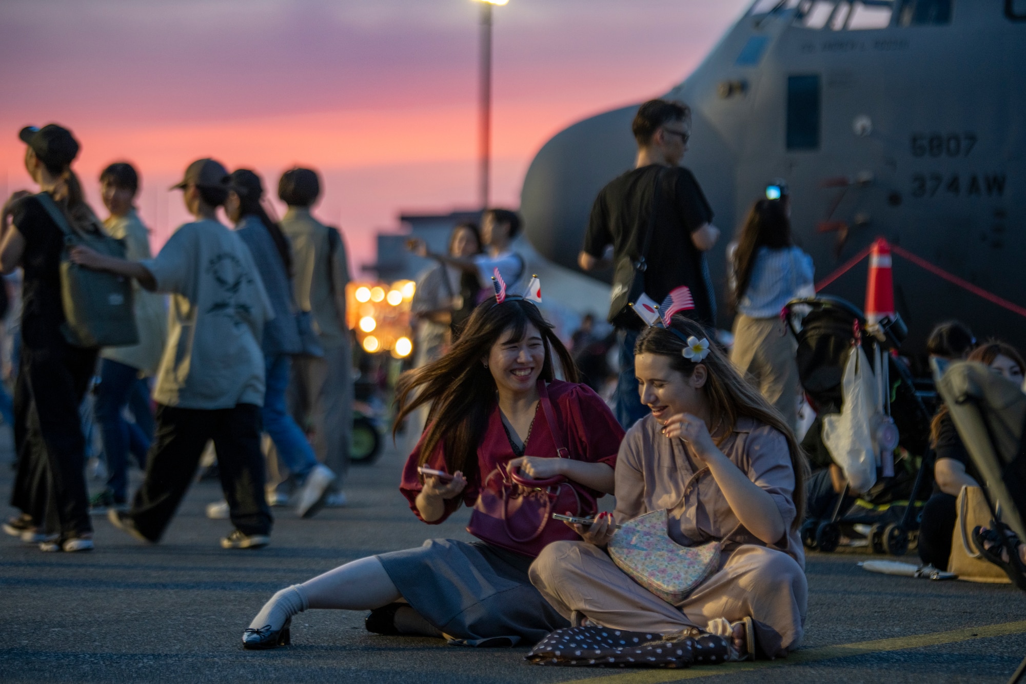 Community members sit on the ground near a C-130J Super Hercules assigned to the 36th Airlift Squadron at the 2024 Japanese-American Friendship Festival at Yokota Air Base.