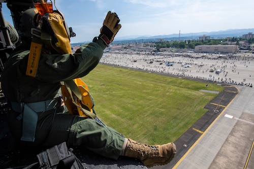 Senior Airman Kayli Rodriguez, 459th Airlift Squadron flight engineer, waves to event-goers at the 2024 Japanese-American Friendship Festival at Yokota Air Base