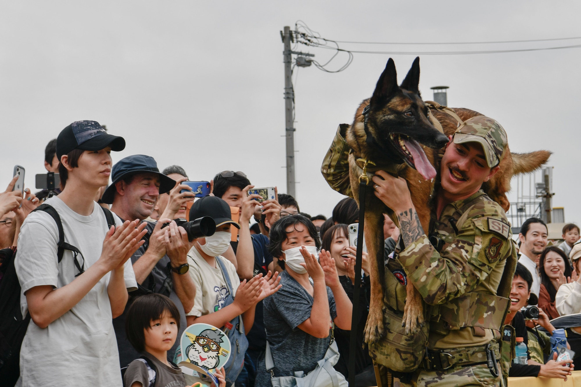 A military working dog over the shoulder of her handler to celebrate a demonstration for a crowd