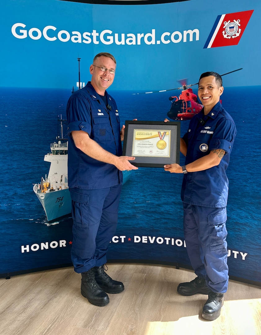 Chief Petty Officer Deren Perez, a figure of inspiration and leadership within the U.S. Coast Guard, is presented with the U.S. Coast Guard's Elite Male Athlete of the Year award by Capt. Nick Simmons, commander of U.S. Coast Guard Forces Micronesia Sector Guam, at the newly relocated recruiting office in Tamuning, Guam, on May 17, 2024. The award, presented on behalf of the U.S. Coast Guard MWR and the Community Services Command, is a testament to his exceptional athletic abilities and his unwavering dedication to his community. (U.S. Coast Guard photo by Chief Warrant Officer Sara Muir)