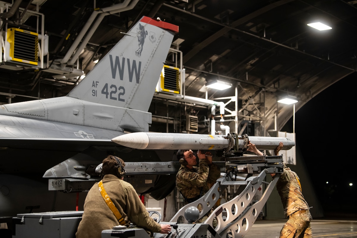 U.S. Air Force Senior Airman Chase Streetman, Staff Sgt. Seon Dodson and Airman 1st Class Victor Lephart, 14th Fighter Generation weapons load team, secure a live AIM-120 advanced medium-range air-to-air missile onto an F-16 Fighting Falcon during a Combat Ammunition Production Exercise at Misawa Air Base, Japan, May 6, 2024.