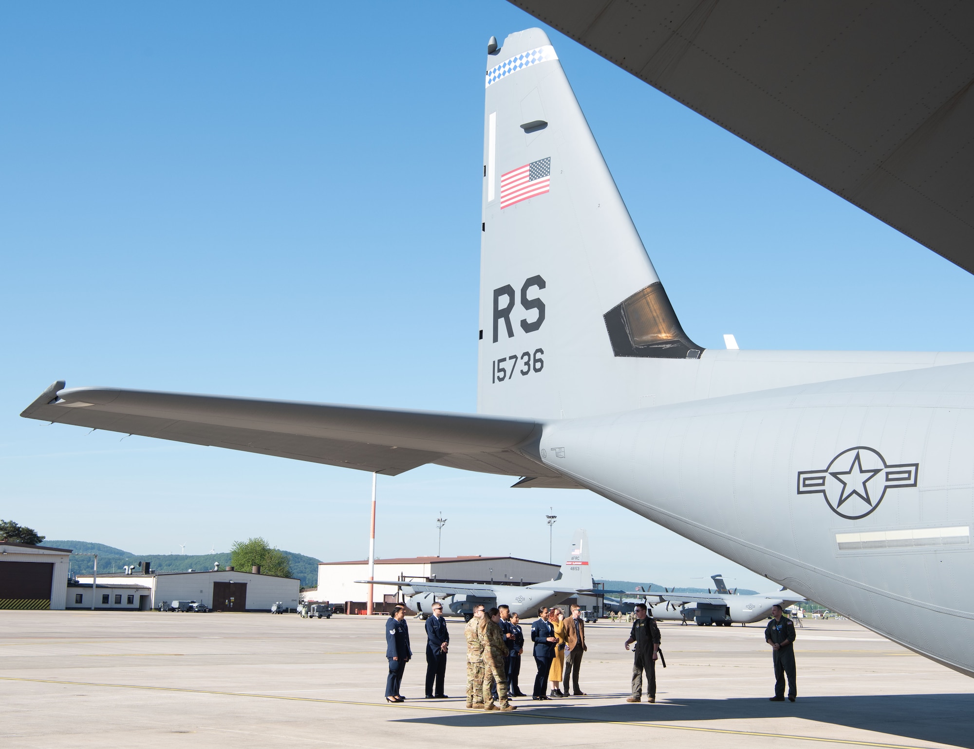 people stand below the tail of a C-130J