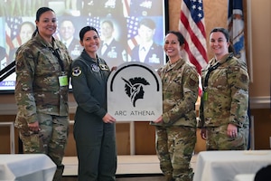 Photo of four Airmen and an ARC Athena sign.