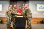 Col. Cathi Cherry, commander of the Professional Education Center; Maj. Gen. Jonathan Stubbs, adjutant general of the Arkansas National Guard; Lt. Col. Elvin Zapata, oldest Soldier serving at PEC; Arkansas Gov. Sarah Huckabee Sanders; Sgt. Rhett Crandall, youngest Soldier serving at PEC; and Lt. Gen. Jon Jensen, director of the Army National Guard, cut the cake at a 50th-anniversary celebration for the PEC on Camp Robinson in North Little Rock, Arkansas, May 16, 2024. PEC is home to more than 480 courses spanning six battalions to train Army National Guard Soldiers and Department of Army civilians in cybersecurity, human resources, logistics, recruiting and retention, strategy and leader development, and finance.