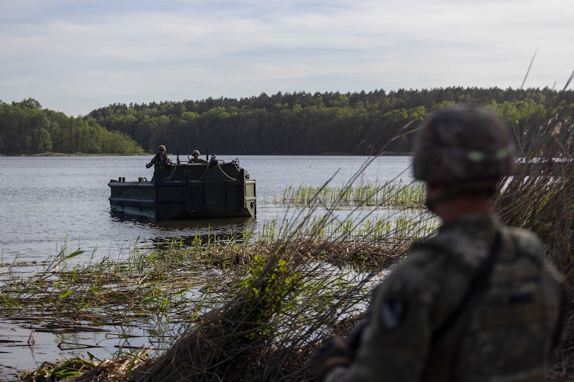 Service members float on a boat as another watches.