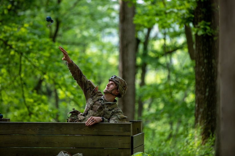 A uniformed soldier throws a grenade during a competition.