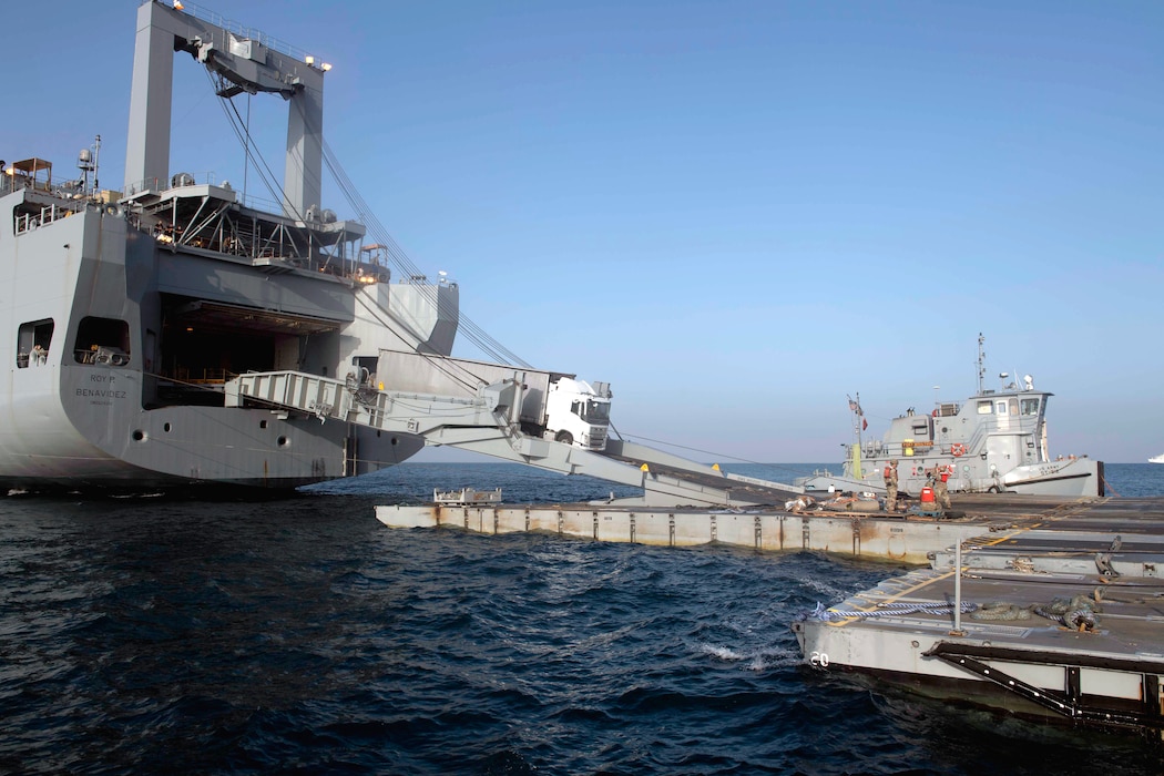 A truck with humanitarian aid drives down the ramp from MV Roy P. Benavidez (T-AKR 306) onto the roll-on/roll-off discharge facility  platform during the delivery of humanitarian assistance to Gaza.