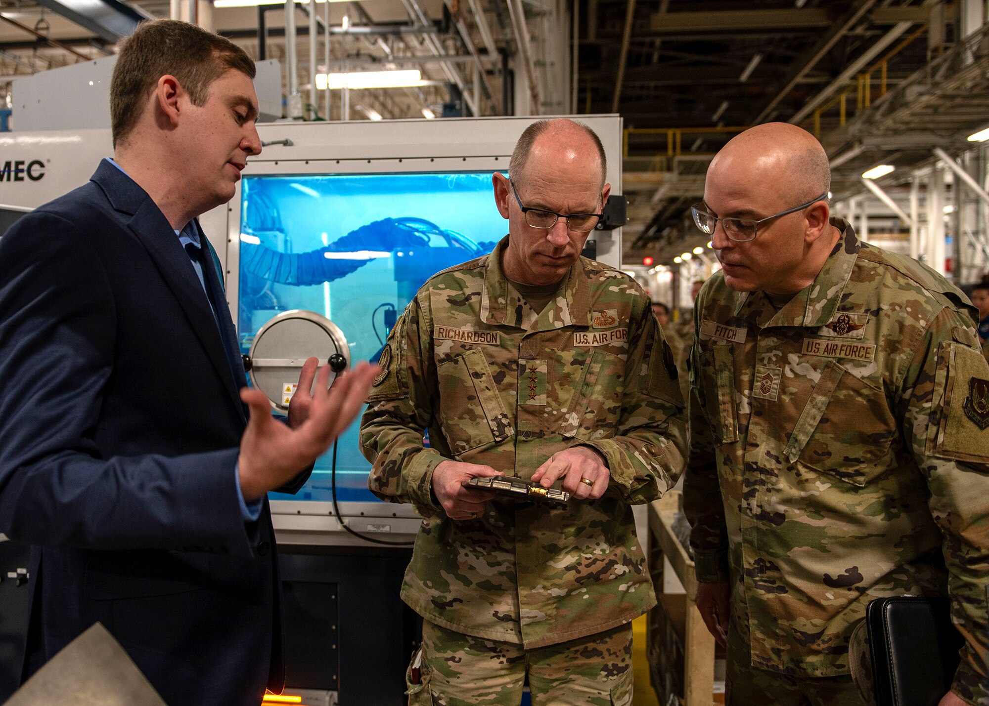 Three men talking together looking at an aircraft part