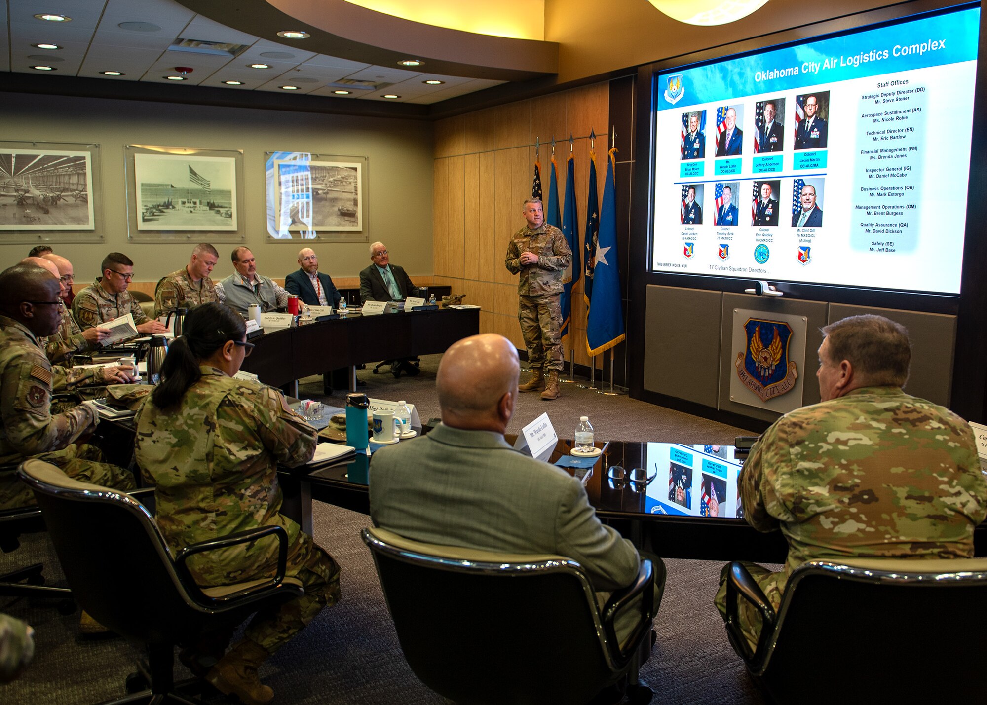 Group of people at semicircular conference table listening to briefing
