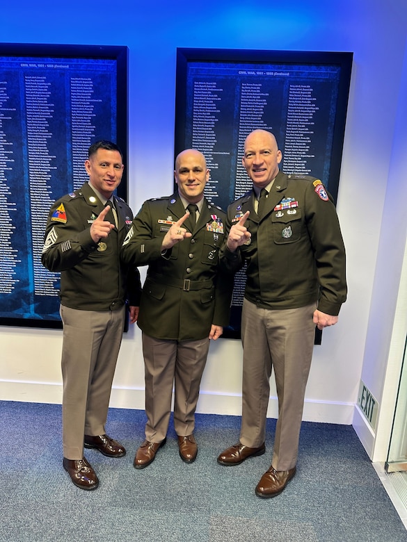 Male U.S. Army Soldier poses with USAREC Commanding General and Command Sergeant Major at the Hall of Heroes