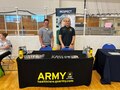 Two male U.S. Army Medicine Recruiters pose at a U.S. Army Medical booth at an event