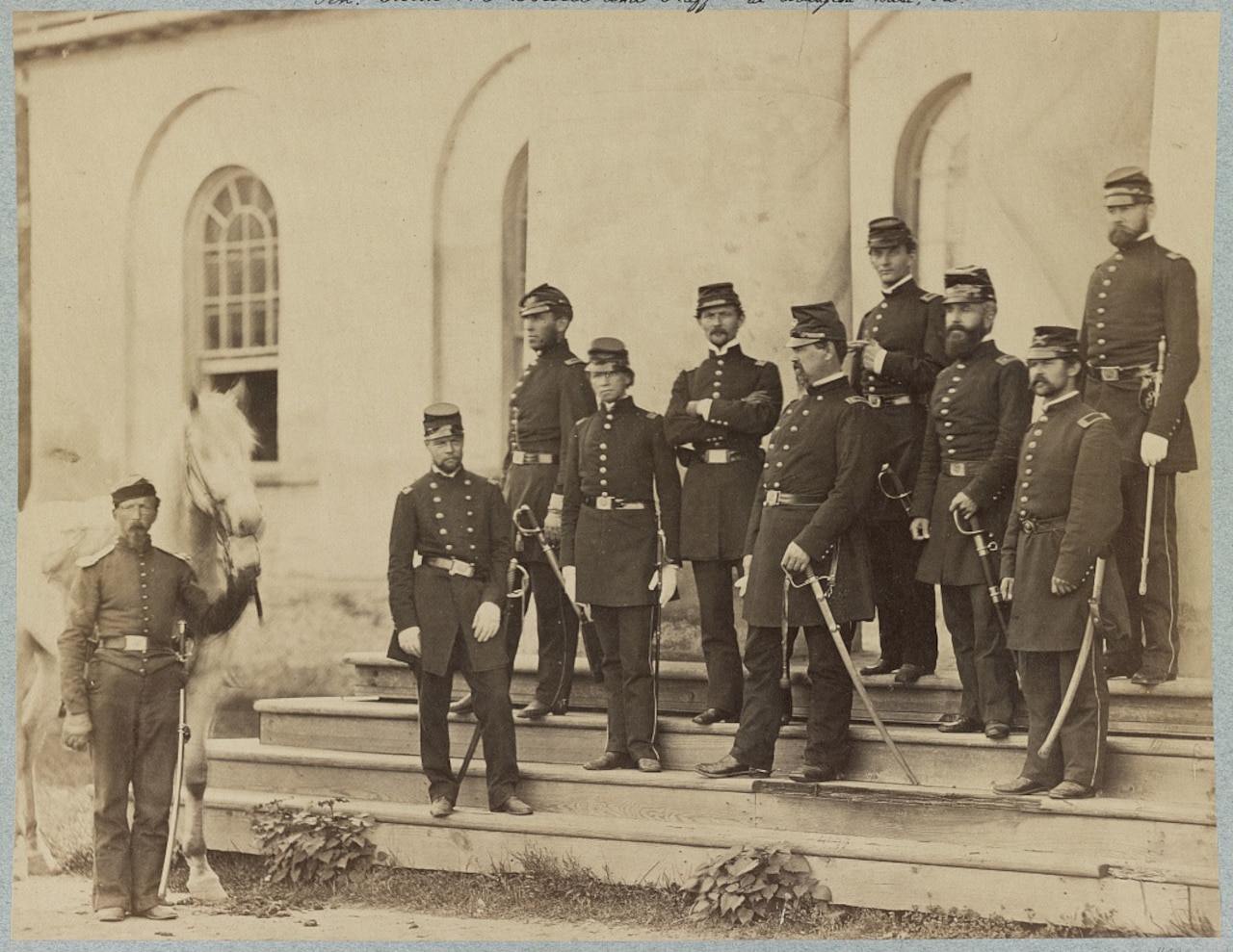 A group of soldiers stand on the steps of a large house.