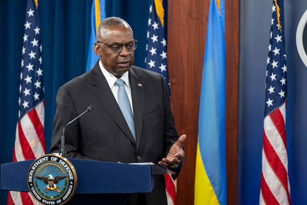 Secretary of Defense Lloyd J. Austin III speaks while standing at a lectern with the American and Ukrainian flags in background.