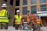 Men in military uniforms wearing construction gear and hard hats