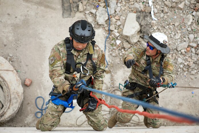 U.S. Air Force Tech Sgt. Frankie Bolaños, left, lowers himself on the line to simulate the rescue of Tech Sgt. Daniel Kolk, both fire contingency instructors with the Pacific Air Force.