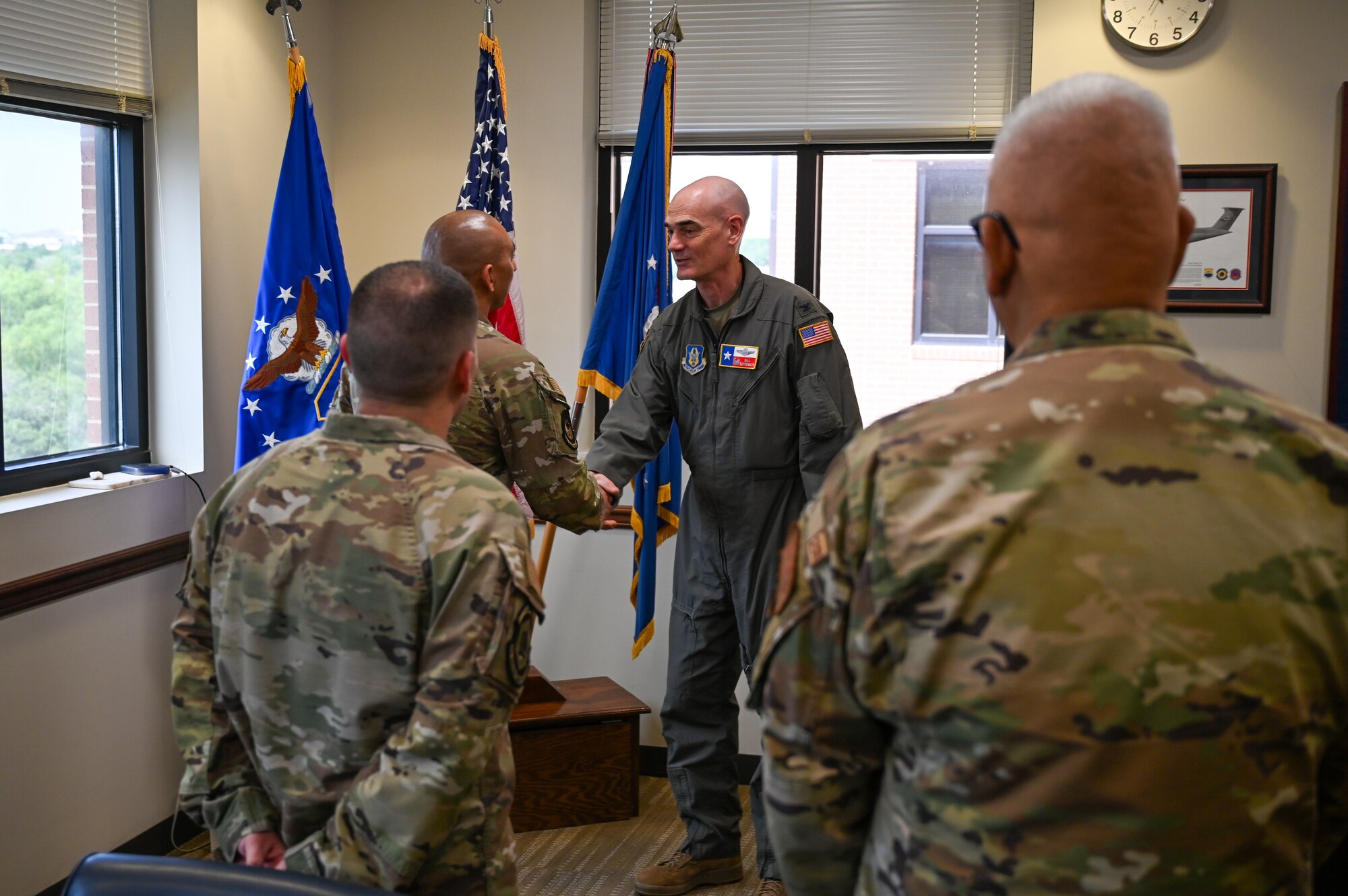 Senior Airman Joe Hernandez, center left, accepts the wing commander’s coin from Col. William Gutermuth, center right, 433rd Airlift Wing commander, for delivering first aid to two people hurt in a crash.