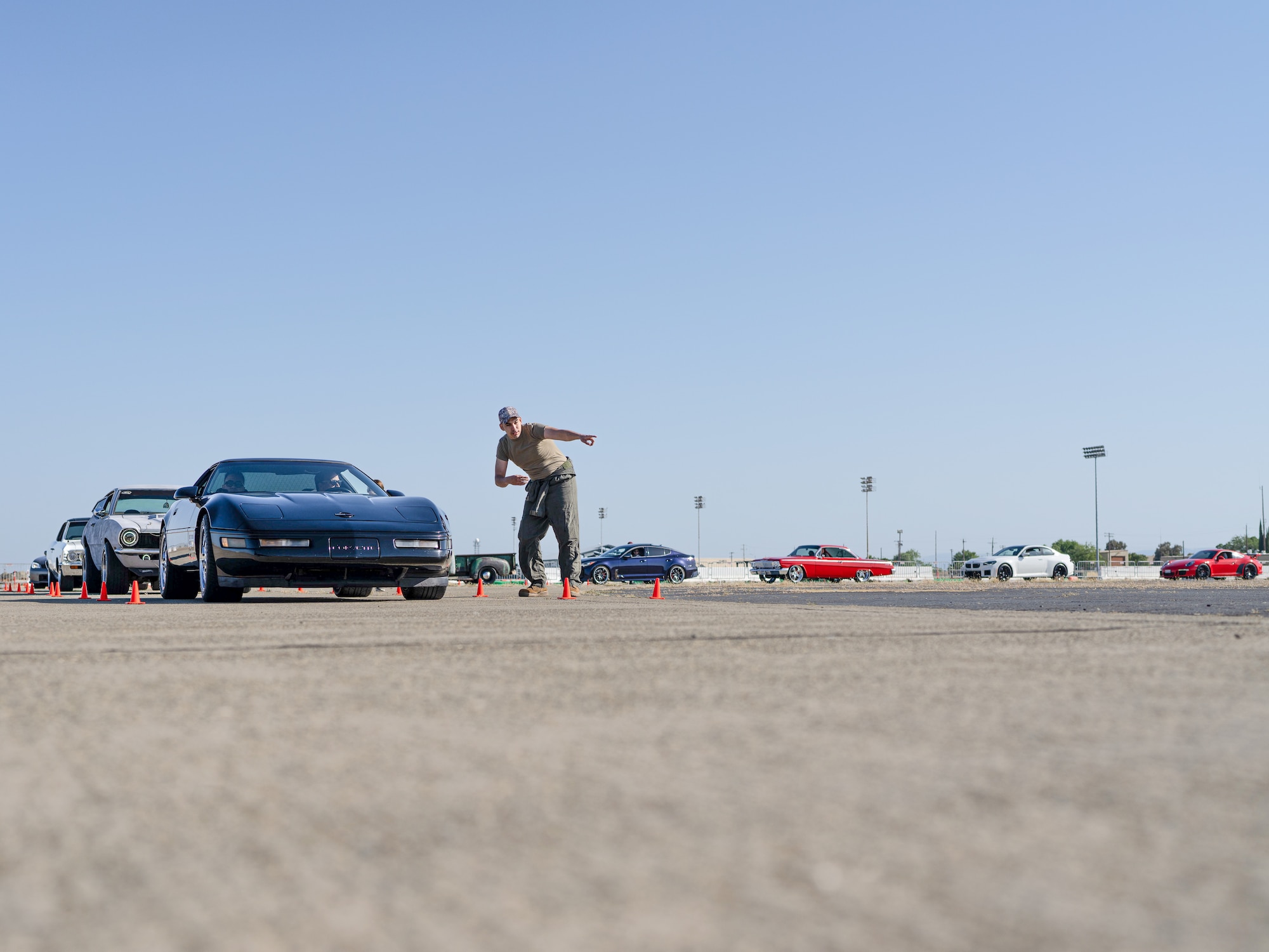 The driver of a black Chevrolet Corvette is given instructions on how to pose next to the U-2 Dragon Lady during the Beale Auto Expo, May 18, 2024, at Beale Air Force Base, California.