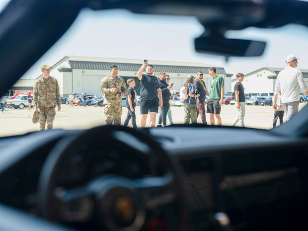 A visitor at the Beale Auto Expo takes a picture of a Porsche on display, May 18, 2024, at Beale Air Force Base, California.