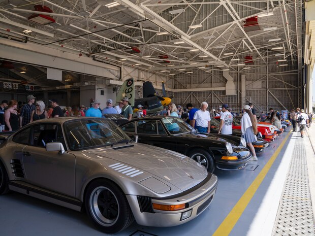 Visitors explore a hangar housing a Hawker Sea Fury and a collection of Porsches during the Beale Auto Expo, May 18, 2024, at Beale Air Force Base, California.