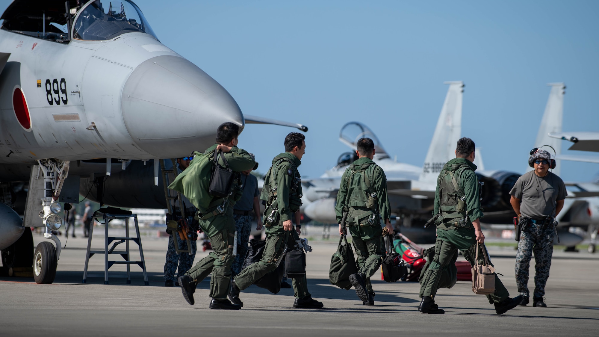 JASDF pilots step to F-15J Eagles on a flightline.