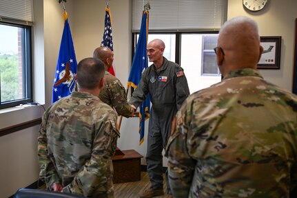 Senior Airman Joe Hernandez, center left, accepts the wing commander’s coin from Col. William Gutermuth, center right, 433rd Airlift Wing commander, for delivering first aid to two people hurt in a crash.
