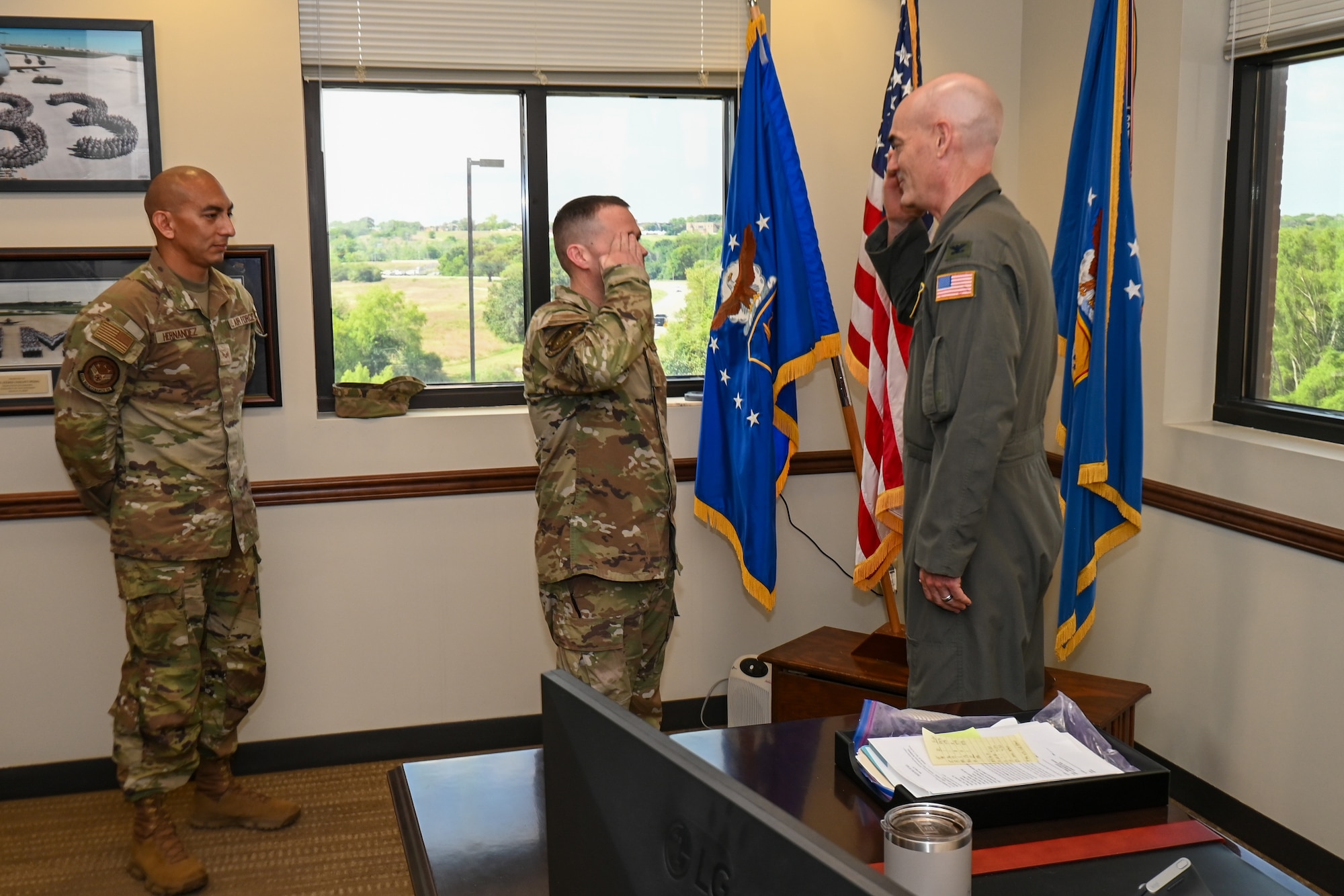 Chief Master Sgt. Kurtis Albright, center, salutes Col. William Gutermuth, right, 433rd Airlift Wing commander, after receiving the wing commander’s coin for delivering first aid to two people hurt in a crash.