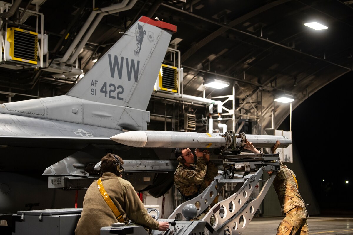 U.S. Air Force Senior Airman Chase Streetman, Staff Sgt. Seon Dodson and Airman 1st Class Victor Lephart, 14th Fighter Generation weapons load team, secure a live AIM-120 advanced medium-range air-to-air missile onto an F-16 Fighting Falcon during a Combat Ammunition Production Exercise at Misawa Air Base, Japan, May 6, 2024.
