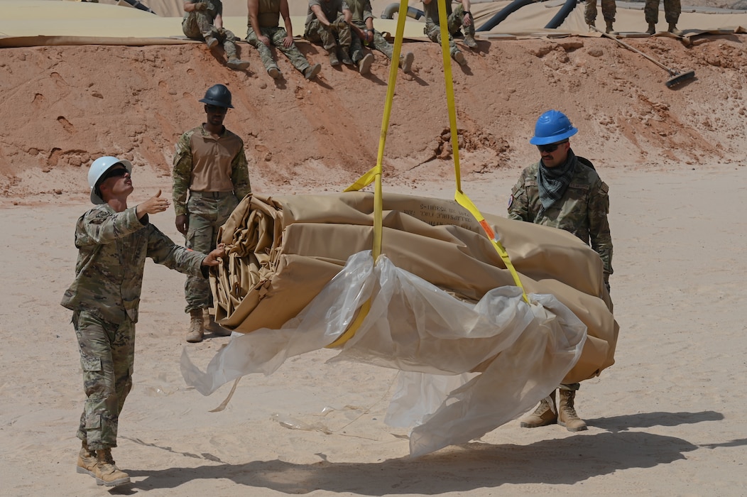 U.S. Air Force Airmen assigned to the 378th
Air Expeditionary Wing assist a crane placing
down a fuel bladder at an undisclosed location
within the U.S. Central Command area of
responsibility, May 17, 2024. Fuel bladders
provide the flexibility for temporary or
permanent use in austere locations to refuel
aircraft and fuel trucks. (U.S. Air Force photo)