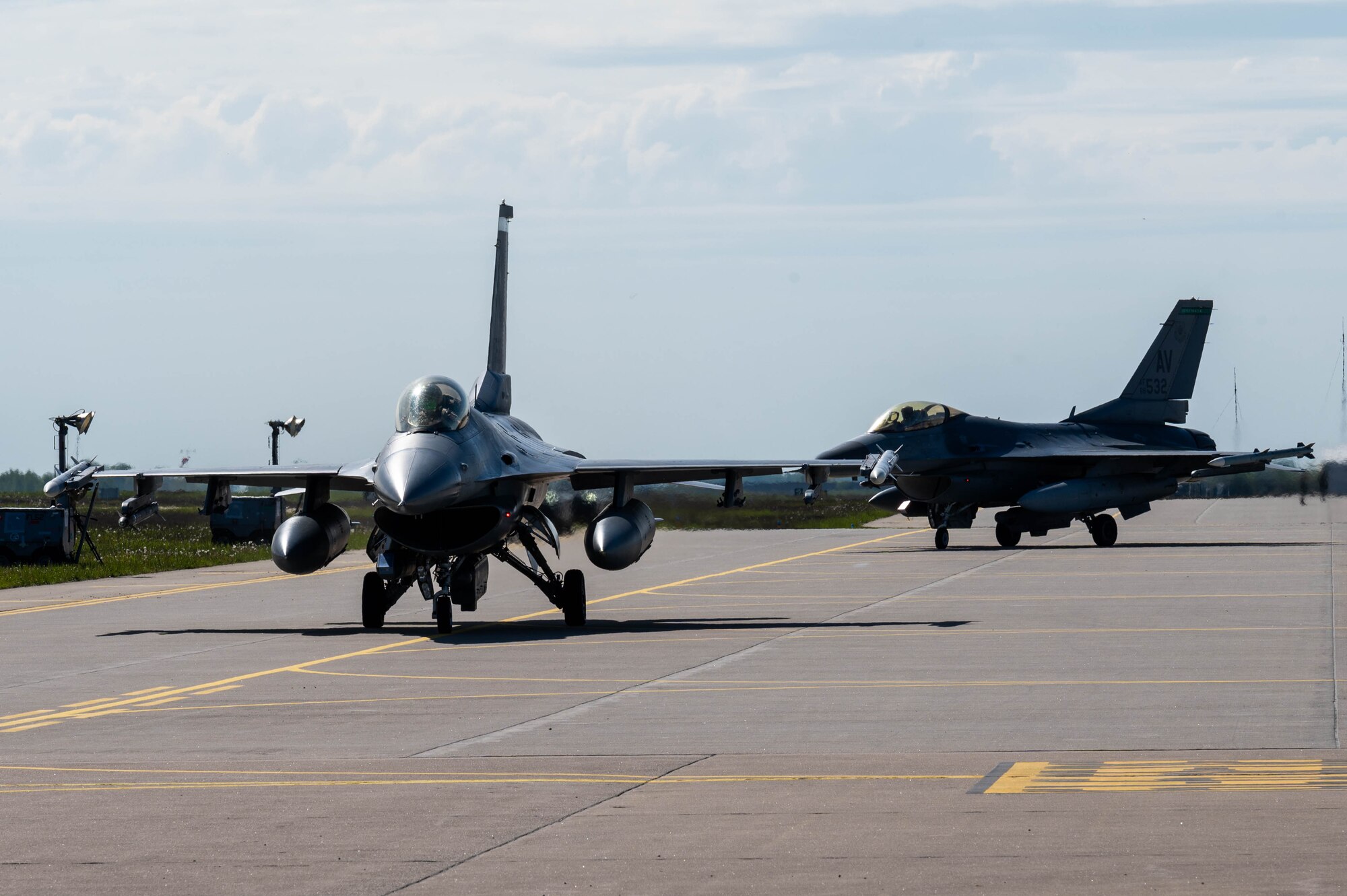 F-16s taxi down a runway.