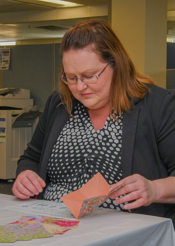 Woman sitting at table folding paper