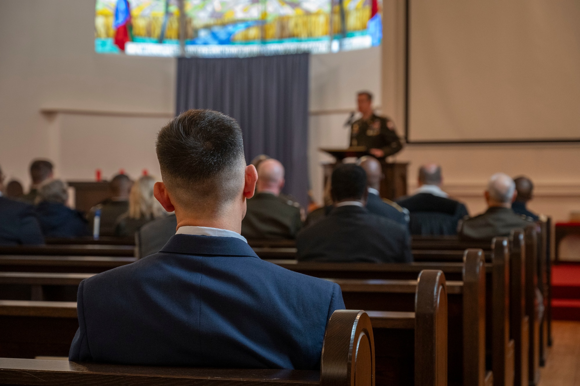 People watch a guest speaker talk at a memorial ceremony